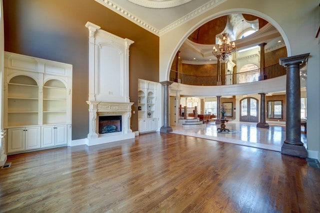 595 S Mount Carmel Rd, Mcdonough, GA 30253 - unfurnished living room featuring a towering ceiling, decorative columns, wood finished floors, built in shelves, and ornamental molding