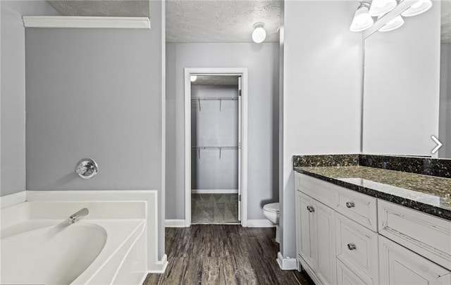 1332 Adcox Sq, Stone Mountain, GA 30088 - bathroom with toilet, a bath, vanity, wood finished floors, and a spacious closet