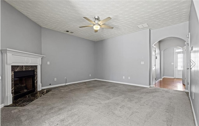 1332 Adcox Sq, Stone Mountain, GA 30088 - unfurnished living room featuring carpet flooring, a ceiling fan, a high end fireplace, arched walkways, and a textured ceiling