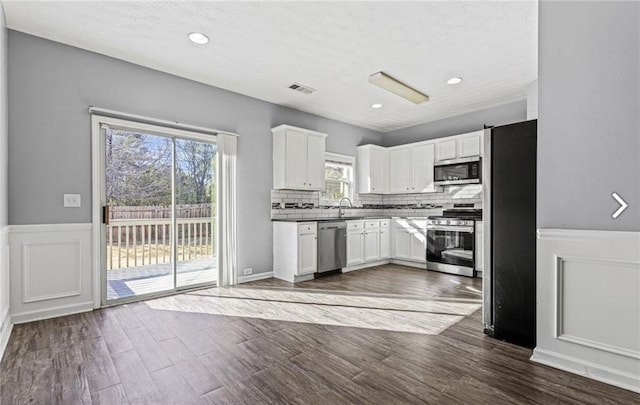 1332 Adcox Sq, Stone Mountain, GA 30088 - kitchen featuring appliances with stainless steel finishes, a wainscoted wall, a sink, white cabinets, and backsplash