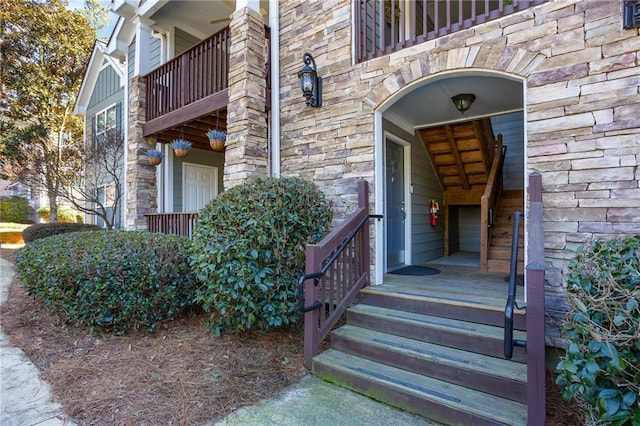 property entrance with stone siding and a balcony