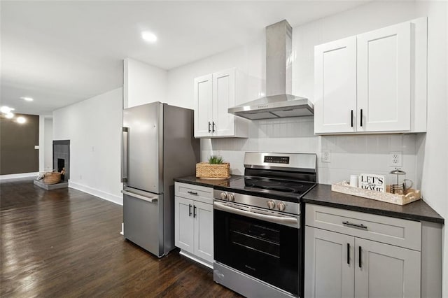 kitchen featuring dark hardwood / wood-style floors, white cabinetry, stainless steel appliances, and wall chimney range hood