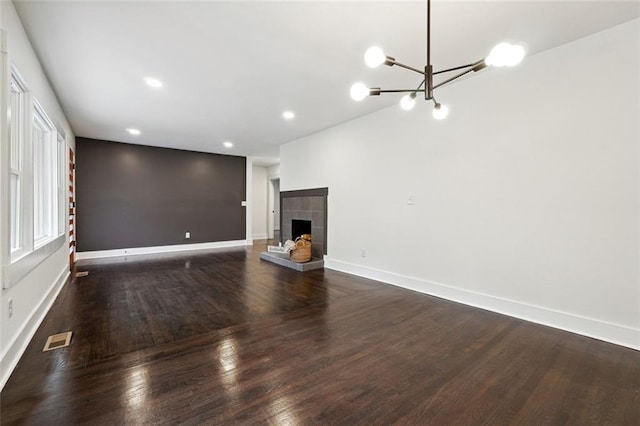 unfurnished living room featuring dark wood-type flooring, a fireplace, and a chandelier