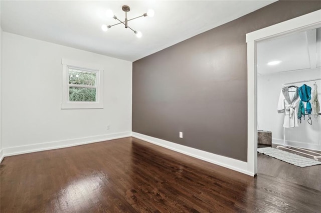 empty room with wood-type flooring and an inviting chandelier