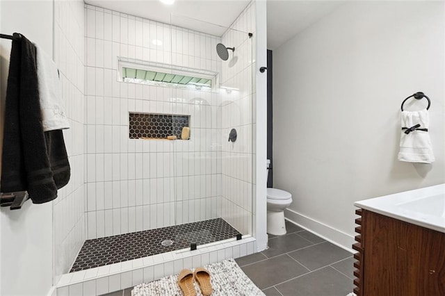 bathroom featuring tile patterned floors, vanity, a tile shower, and toilet