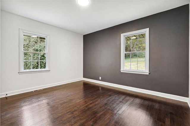 spare room with a healthy amount of sunlight and dark wood-type flooring