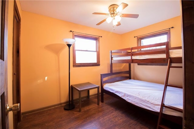 bedroom with multiple windows, ceiling fan, and dark hardwood / wood-style flooring