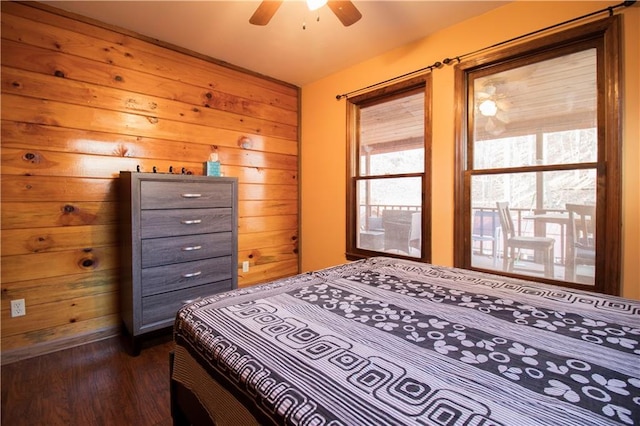 bedroom with ceiling fan, wood walls, and dark hardwood / wood-style flooring