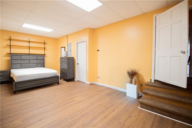 bedroom with a paneled ceiling and light wood-type flooring