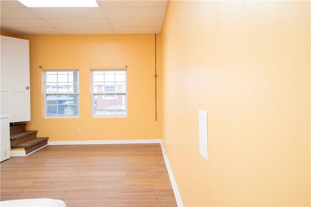 empty room with a paneled ceiling and light hardwood / wood-style floors