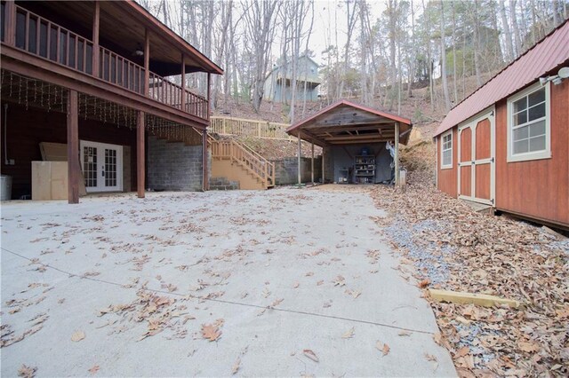 view of property exterior featuring a storage unit, a wooden deck, and french doors