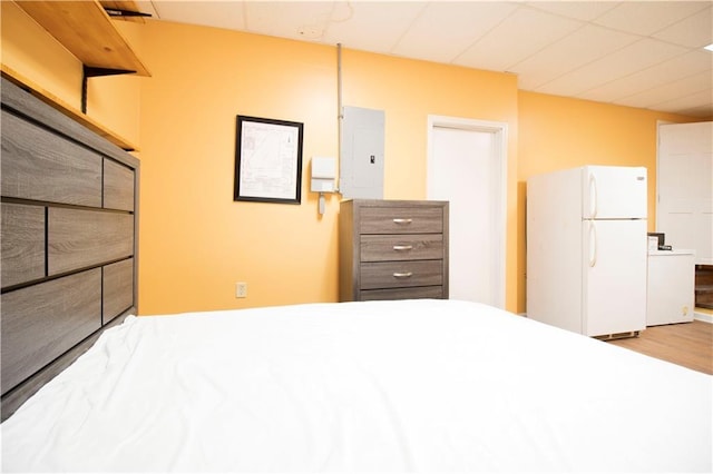 unfurnished bedroom featuring white refrigerator, light wood-type flooring, and electric panel