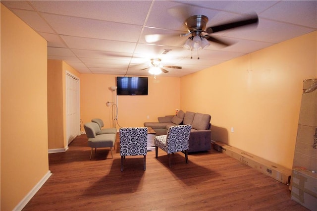 sitting room with ceiling fan, a drop ceiling, and wood-type flooring