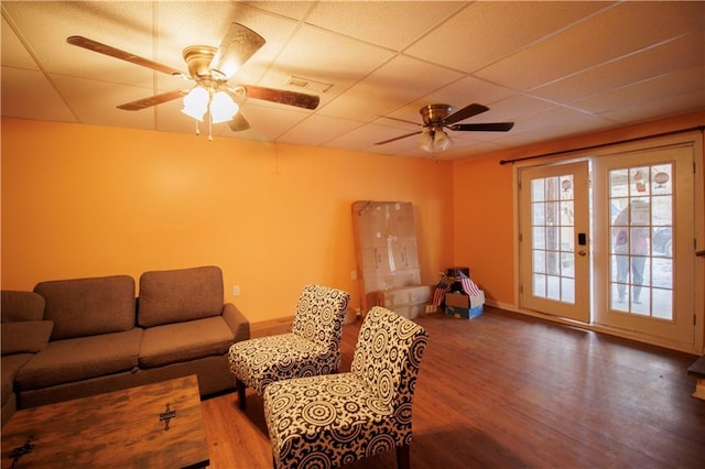 living room featuring ceiling fan, hardwood / wood-style floors, and a drop ceiling