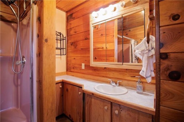 bathroom with vanity, wood walls, and walk in shower