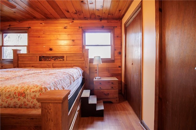 bedroom featuring multiple windows, wooden walls, wooden ceiling, and light wood-type flooring