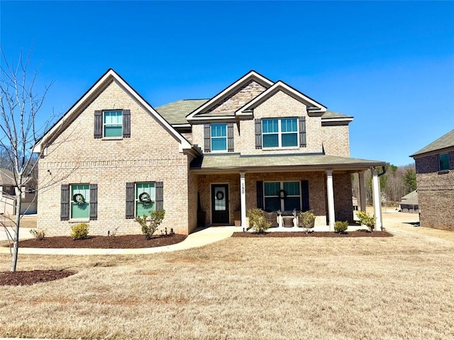 craftsman inspired home with a front yard, covered porch, and brick siding