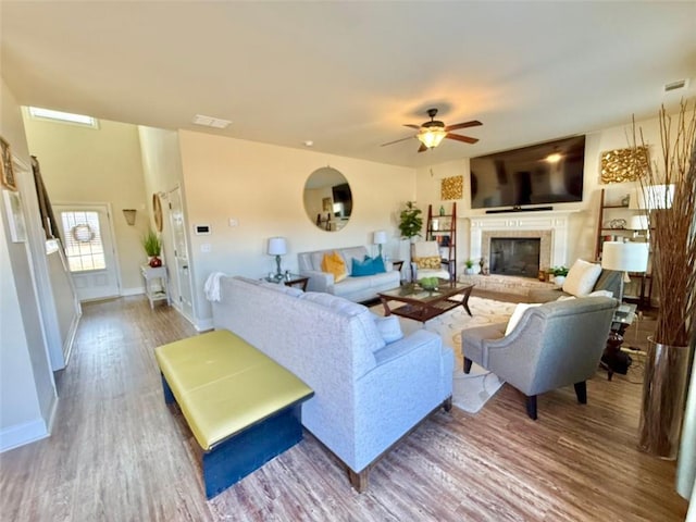 living area with visible vents, a ceiling fan, wood finished floors, and a fireplace