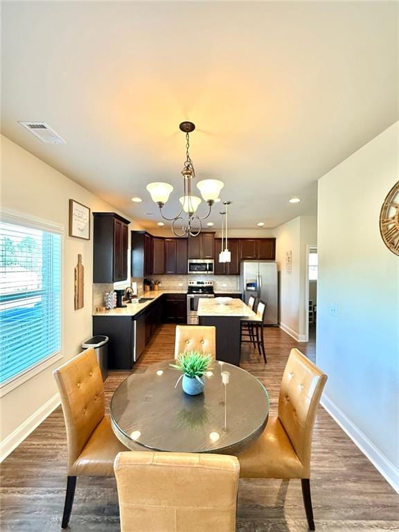 dining space with visible vents, baseboards, light wood-style floors, and an inviting chandelier