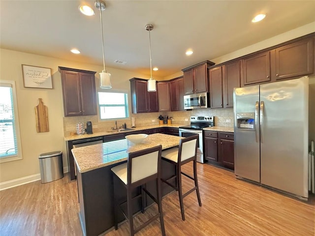 kitchen with dark brown cabinetry, light wood finished floors, appliances with stainless steel finishes, and a sink