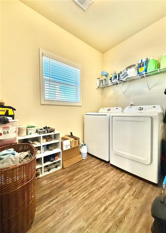 laundry area featuring visible vents, wood finished floors, laundry area, and washer and clothes dryer