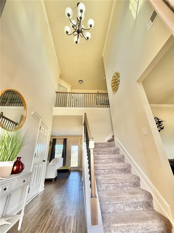 entrance foyer with visible vents, wood finished floors, baseboards, a towering ceiling, and stairs