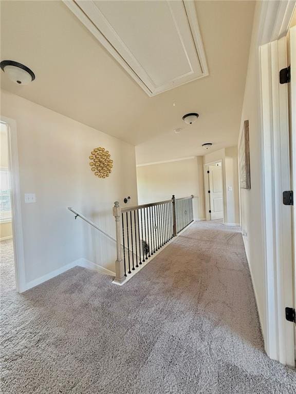 corridor with attic access, carpet flooring, an upstairs landing, and baseboards