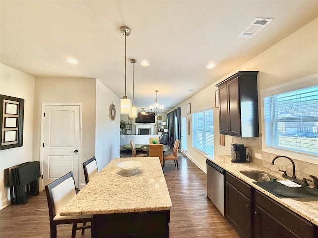 kitchen featuring visible vents, dark wood-type flooring, dark brown cabinetry, dishwasher, and a sink