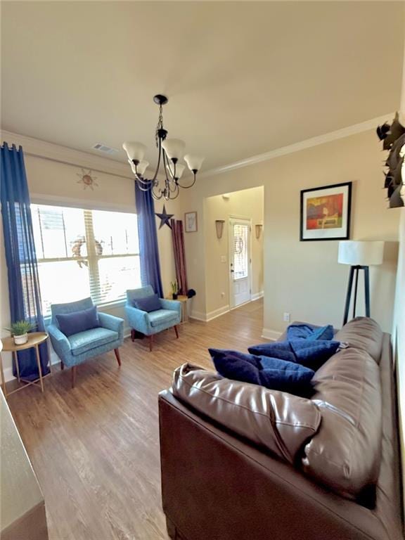 living area with light wood-type flooring, an inviting chandelier, crown molding, and visible vents