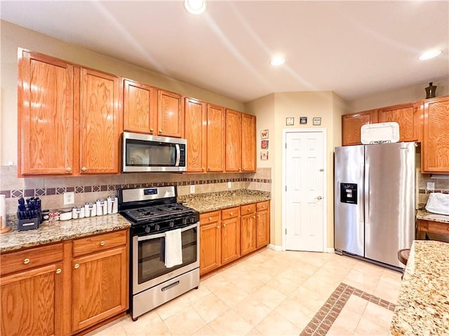 kitchen with light stone counters, decorative backsplash, and stainless steel appliances