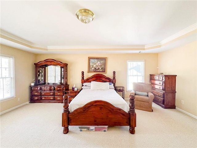 carpeted bedroom with ornamental molding and a tray ceiling