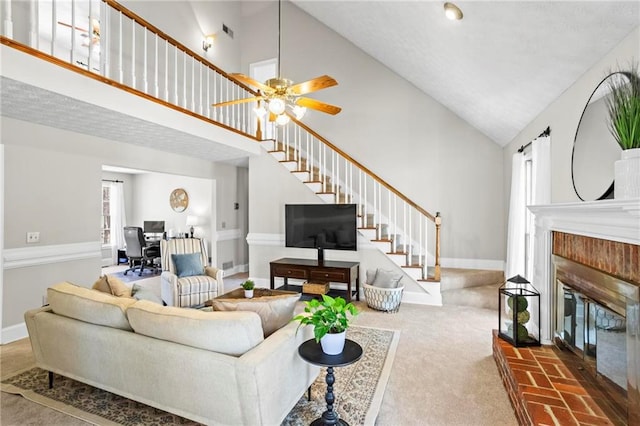 living room with a brick fireplace, high vaulted ceiling, baseboards, carpet flooring, and stairs