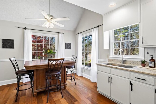 dining room with a ceiling fan, vaulted ceiling, wood finished floors, baseboards, and recessed lighting