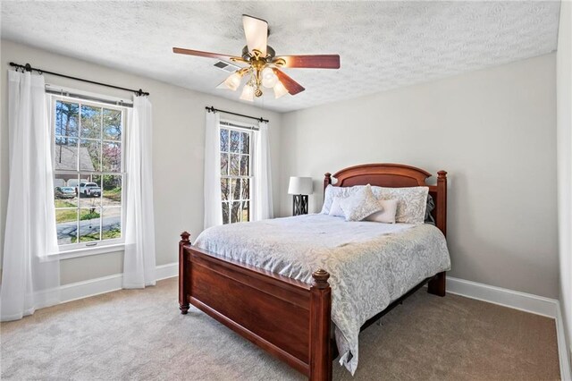 carpeted bedroom with a ceiling fan, a textured ceiling, and baseboards