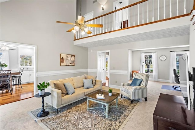 living area featuring carpet floors, ceiling fan, and a high ceiling
