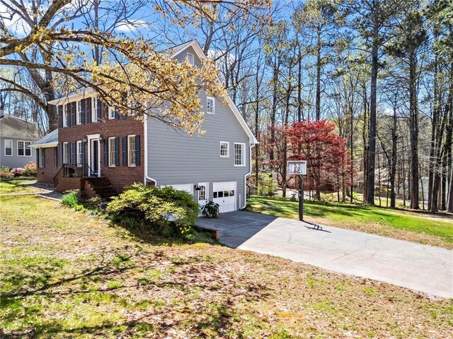view of side of home featuring concrete driveway, a yard, and a garage