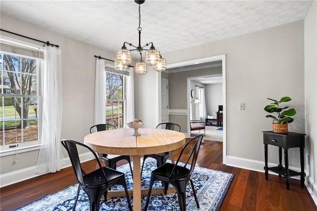 dining space with a textured ceiling, baseboards, an inviting chandelier, and wood finished floors