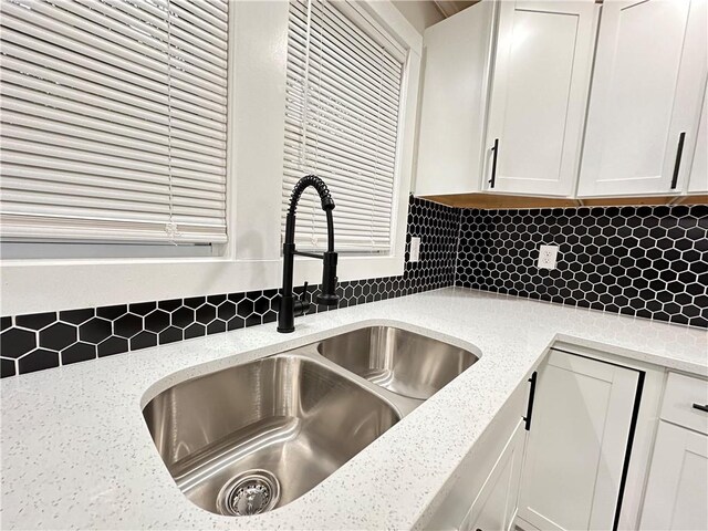 room details featuring light stone countertops, decorative backsplash, sink, and white cabinets