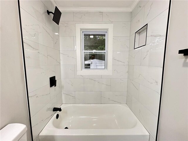 bathroom featuring ornamental molding, tiled shower / bath combo, and toilet