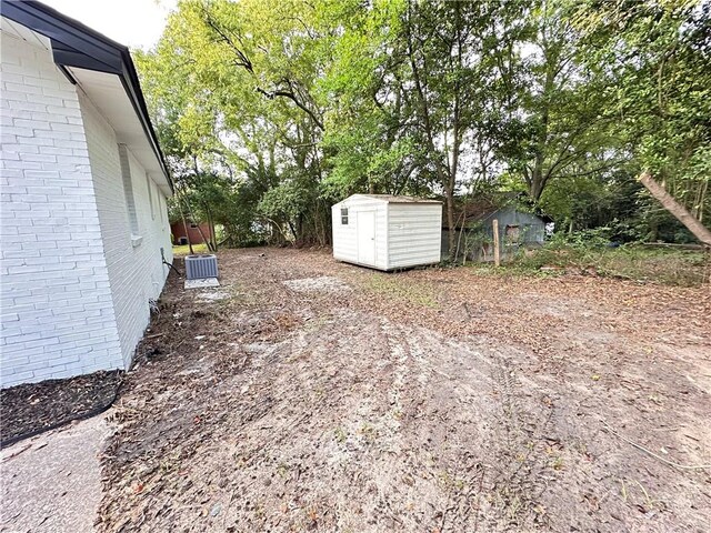 view of yard with central AC unit and a shed