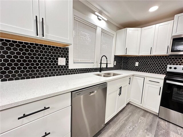 kitchen with decorative backsplash, white cabinetry, stainless steel appliances, light wood-type flooring, and sink