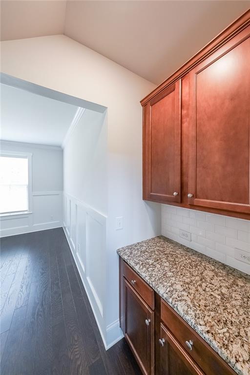 5789 Creek Indian Dr, Sugar Hill, GA 30518 - hallway with dark wood-style flooring, vaulted ceiling, a wainscoted wall, ornamental molding, and a decorative wall