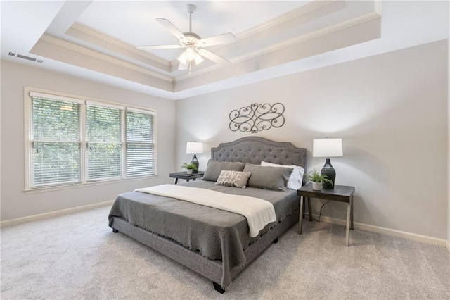 bedroom featuring a raised ceiling, crown molding, carpet floors, baseboards, and ceiling fan
