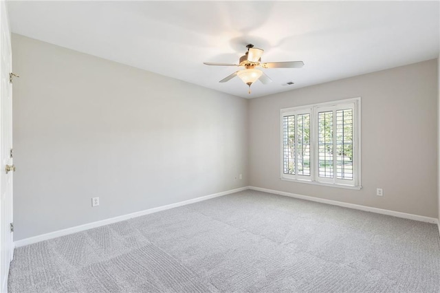 carpeted spare room with a ceiling fan and baseboards