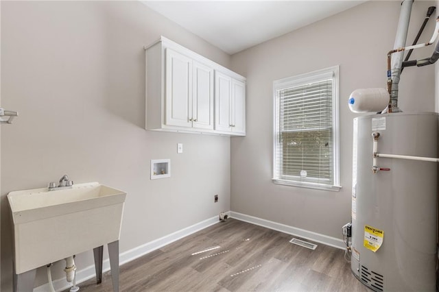 washroom with gas water heater, washer hookup, light wood-style floors, cabinet space, and baseboards