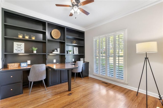 office area featuring built in study area, ornamental molding, ceiling fan, light wood-type flooring, and baseboards