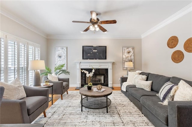living room featuring ceiling fan, crown molding, wood finished floors, a high end fireplace, and baseboards