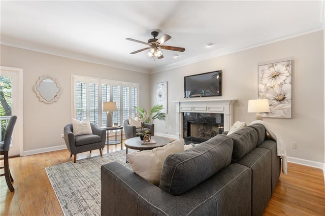 living room featuring a high end fireplace, healthy amount of natural light, ornamental molding, a ceiling fan, and baseboards
