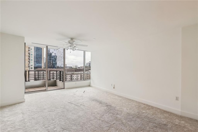 carpeted empty room with ceiling fan and expansive windows