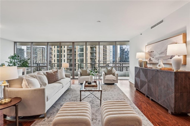 living room featuring dark hardwood / wood-style flooring, a wall of windows, and a healthy amount of sunlight